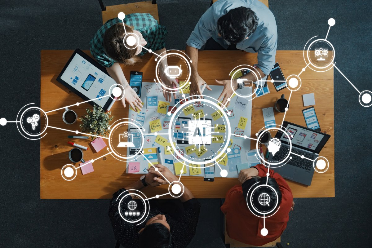 A top-down view of a collaborative team working on AI technology development with digital tools on a wooden table, showcasing creativity and innovation in professional settings. 